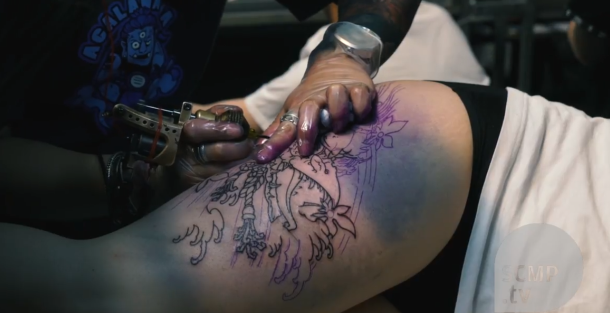 wanita sedang melakukan tato di kulitnya